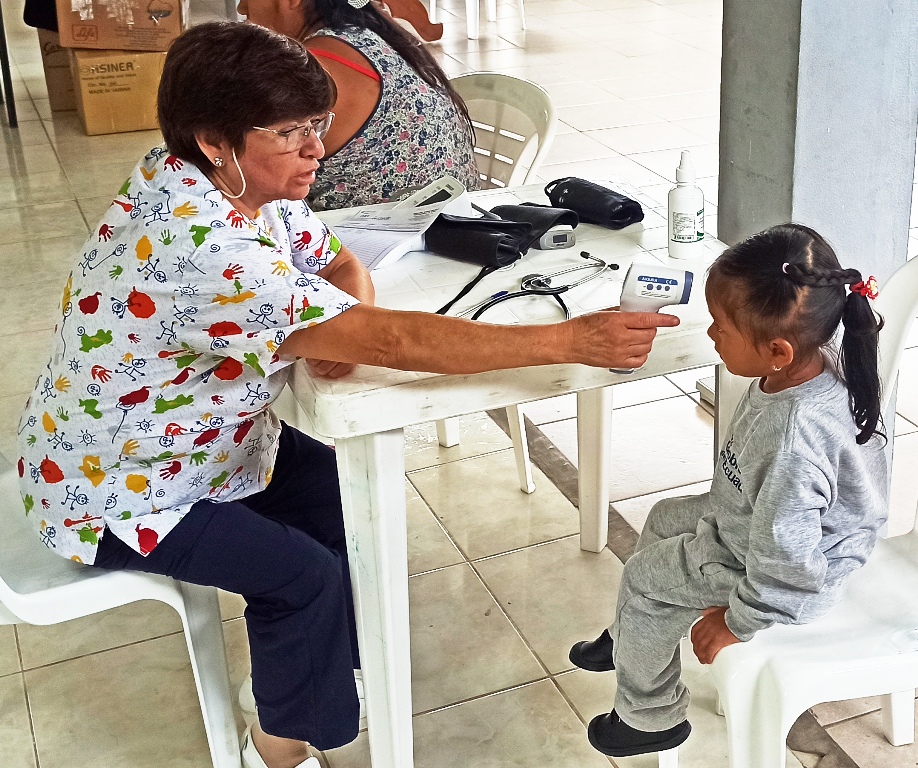 Enfermera del Hospital Padre Carollo toma de signos vitales a una niña de la comunidad Asunción